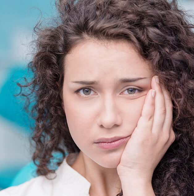 woman holding her jaw in pain