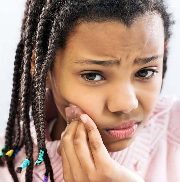 young girl holding her jaw in pain