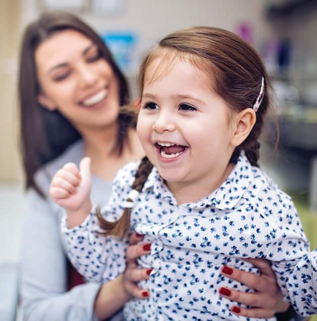 mother holding her daughter while at a dental appointment