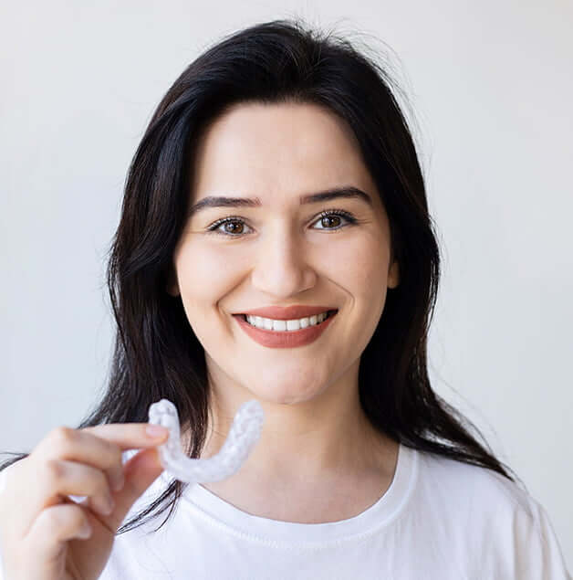 smiling woman holding up a nightguard